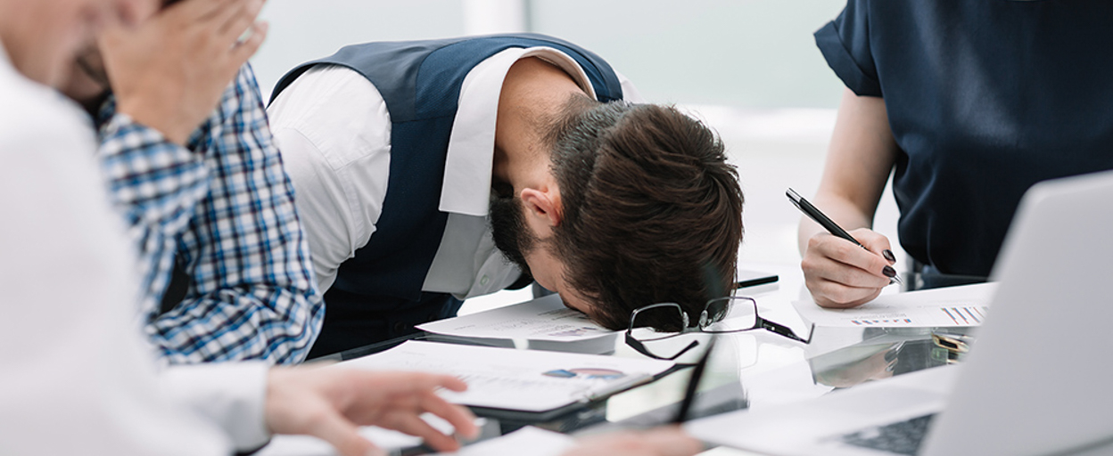 Man who has made a mistake at work, head on desk, disappointed in himself.