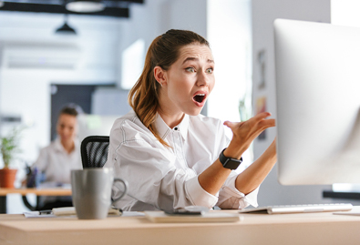 A person looking surprised in front of a computer screen