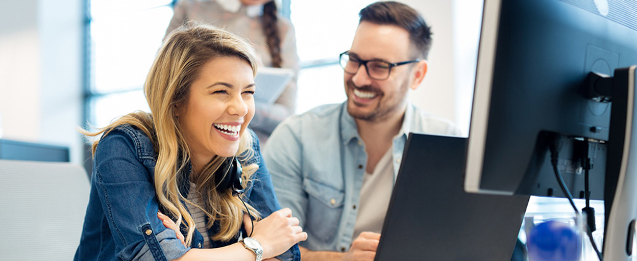 Woman and man laughing in front of computer