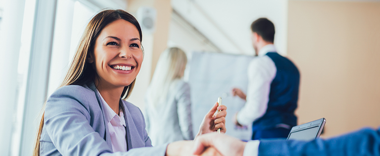 Woman at desk shaking hands with man