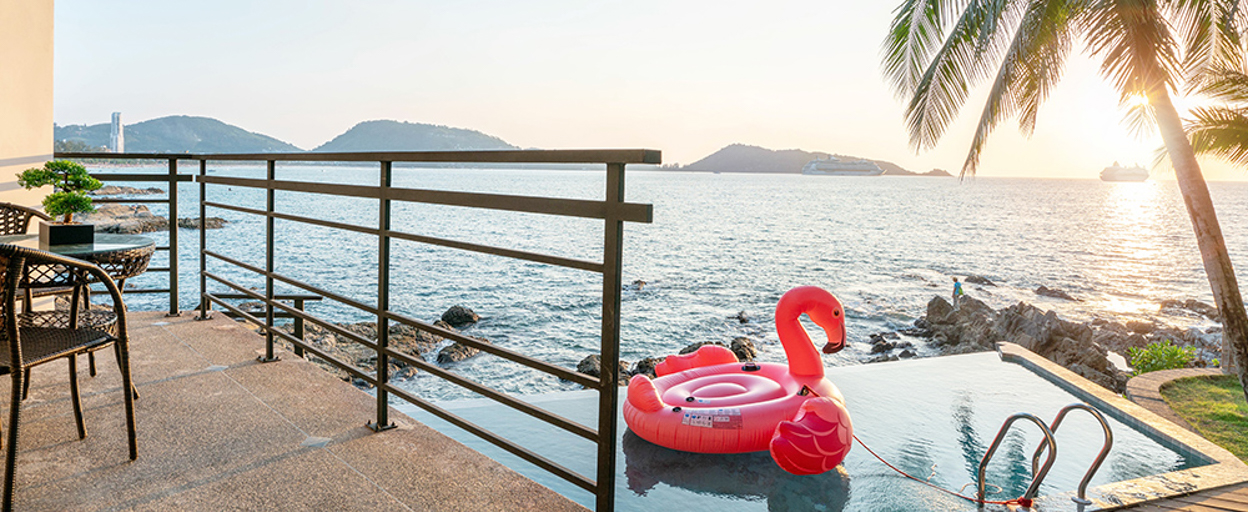 View of ocean overlooking balcony and pool with flamingo floaty