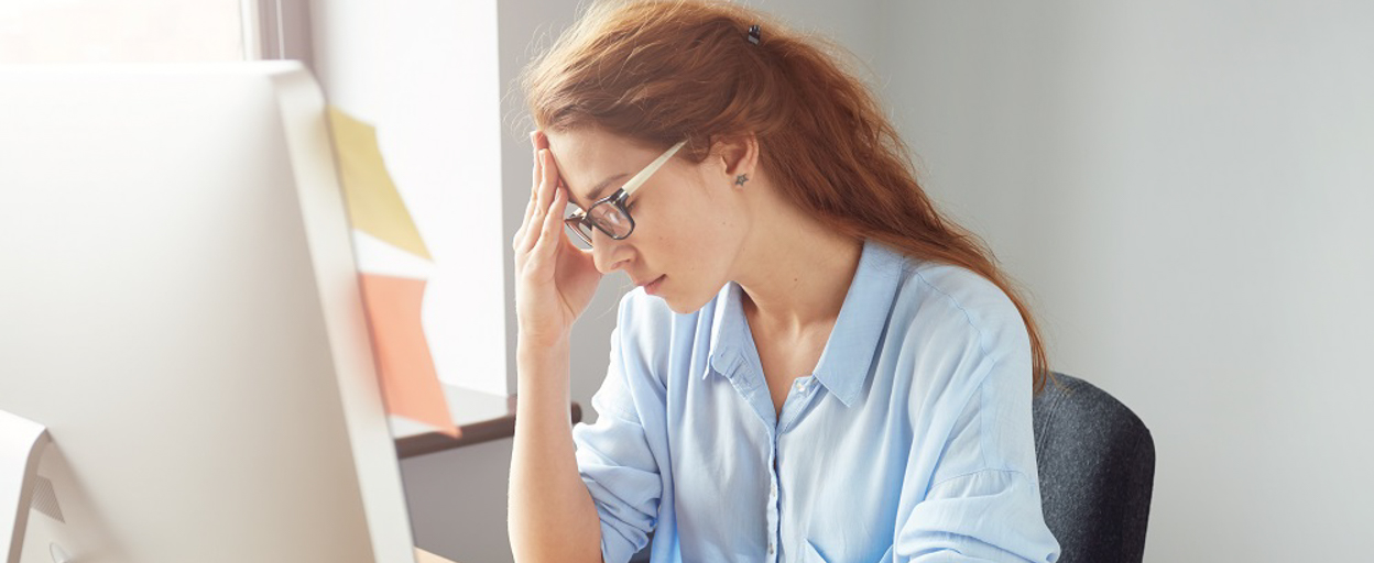 Woman at desk with head in hands