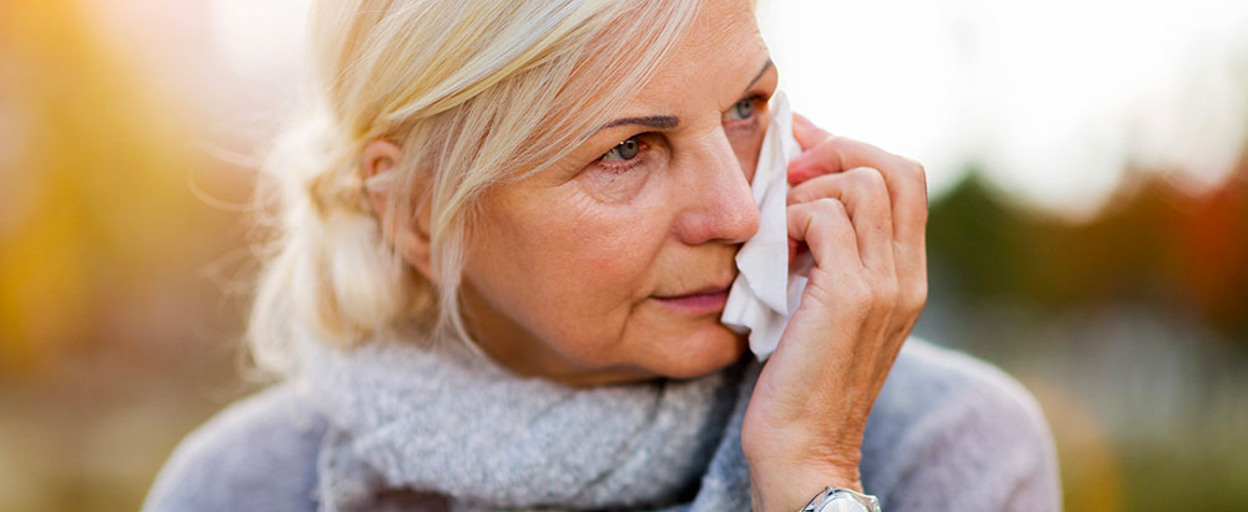 Older woman crying holding tissue to face