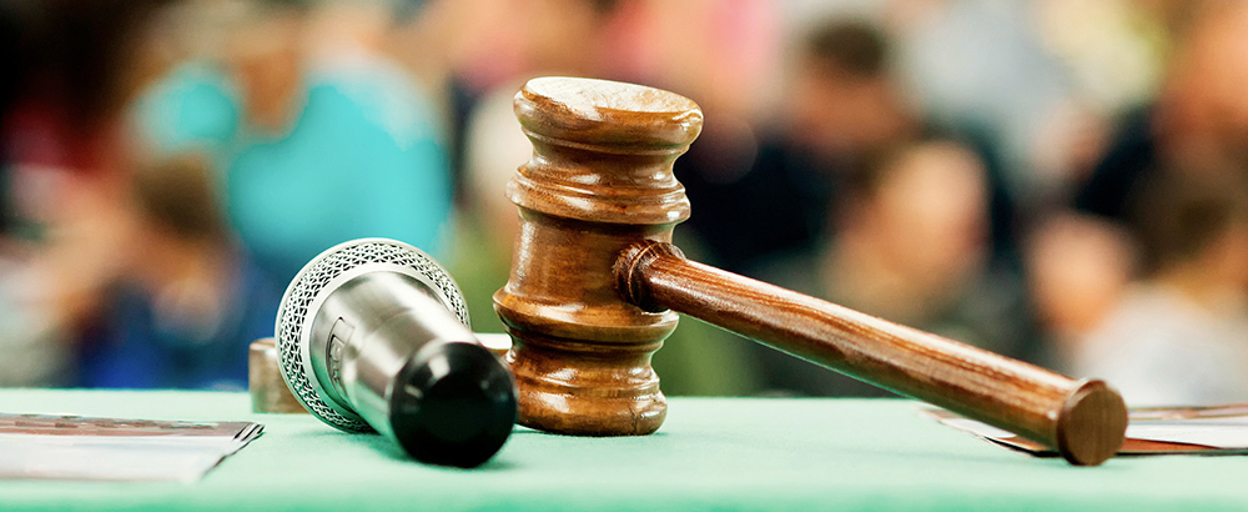 Gavel and microphone on table in front of blurred people