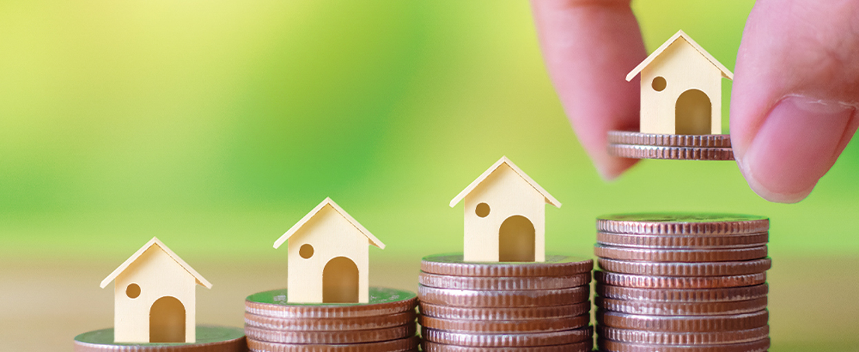 Piles of coins with tiny houses on top
