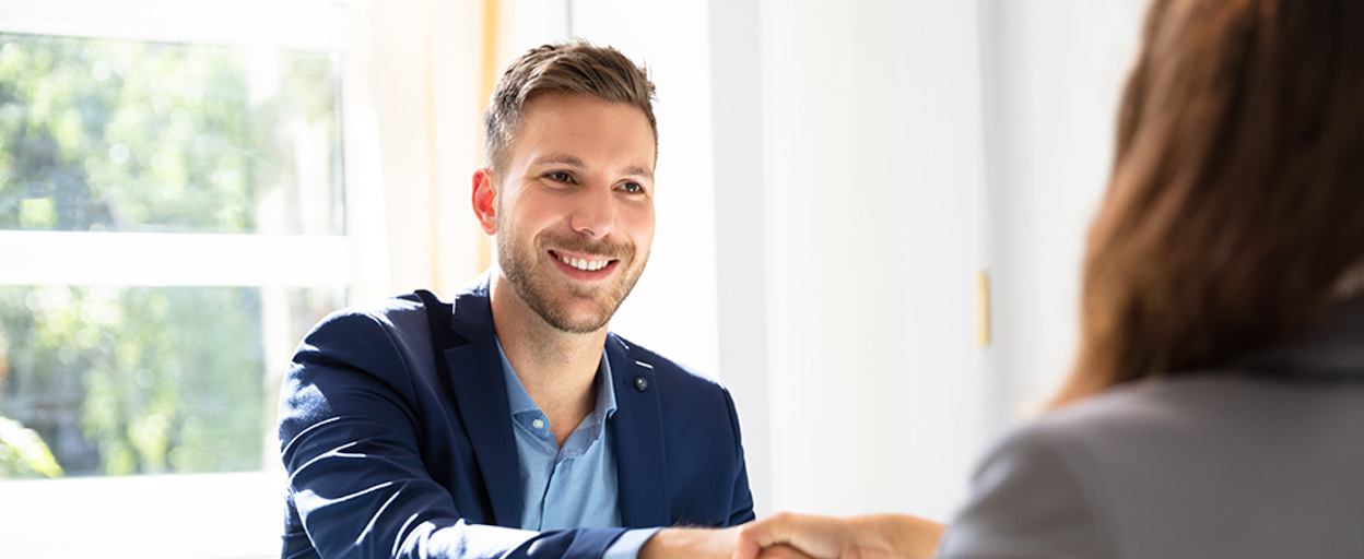 Man smiling shaking hands with woman across table