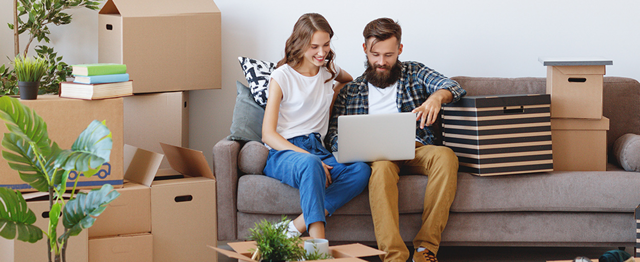 Couple sitting on couch with packing boxes scattered around