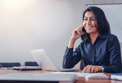 Woman smiling on the phone with laptop and grey background