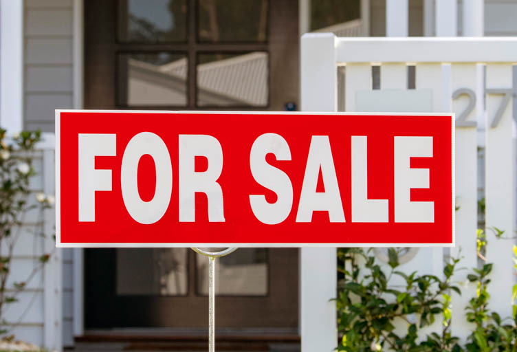 A for sale sign in front of a residential home
