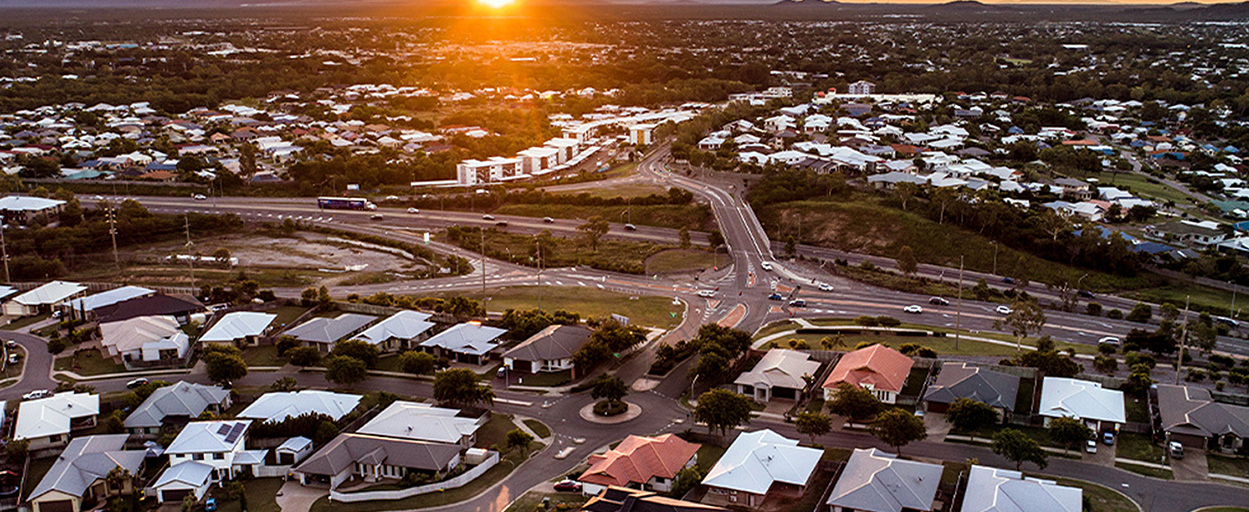 Aerial shot over Townsville suburban houses with sunsetting in background